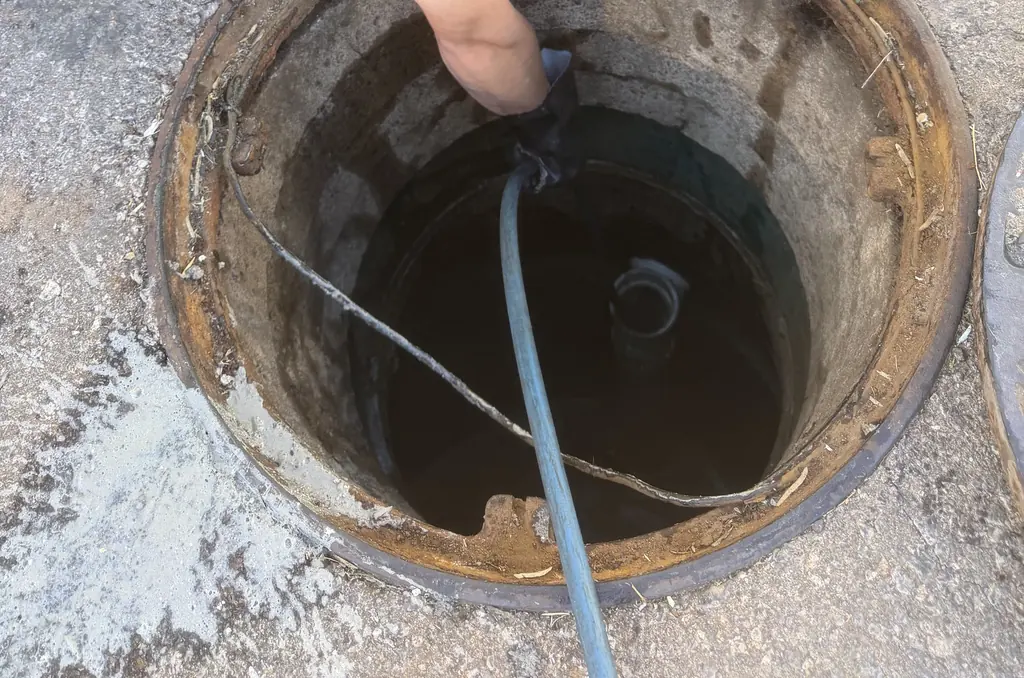 Vac hose lowered into an open manhole on a commercial lot